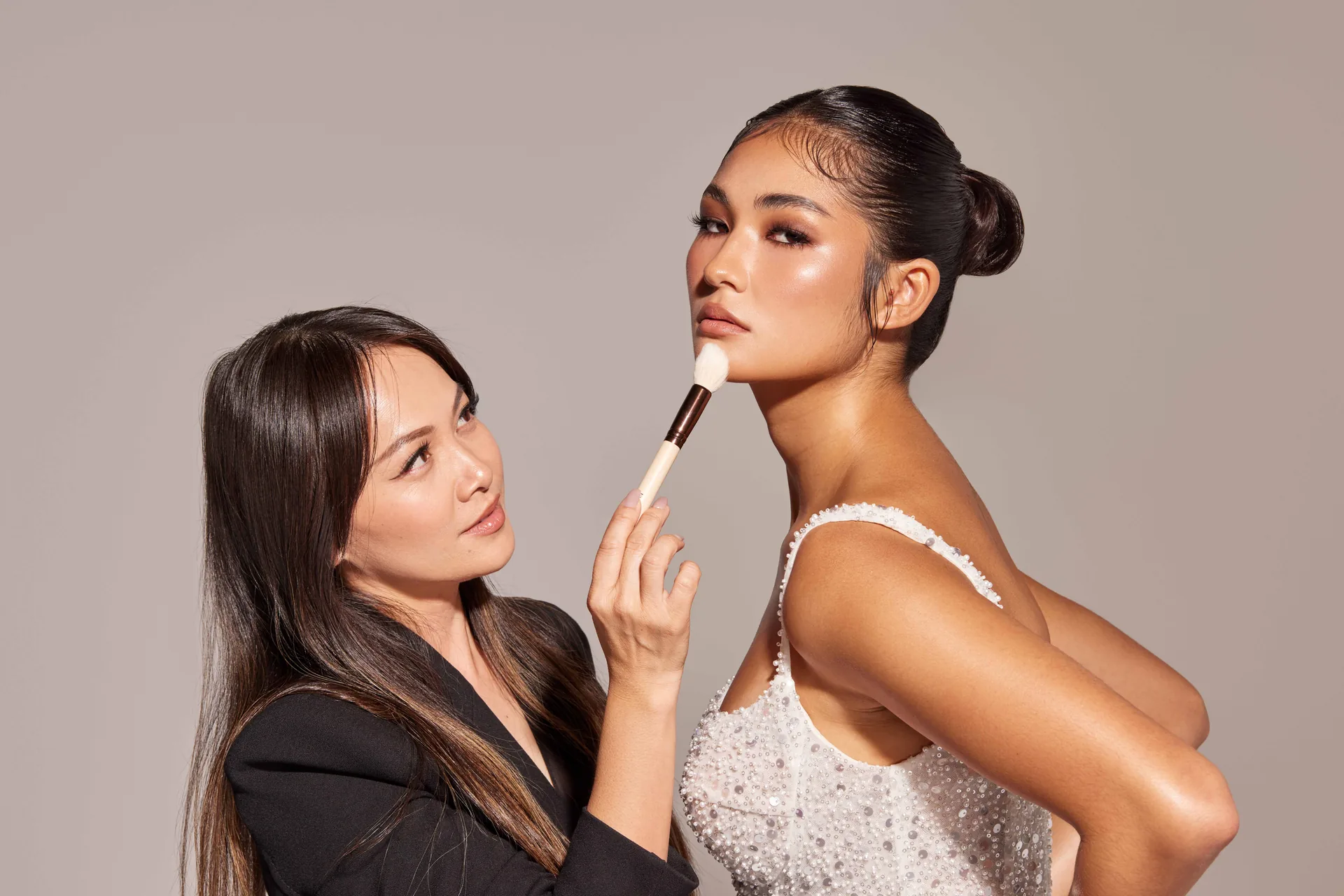Hong Le applying makeup to a model in a beaded gown